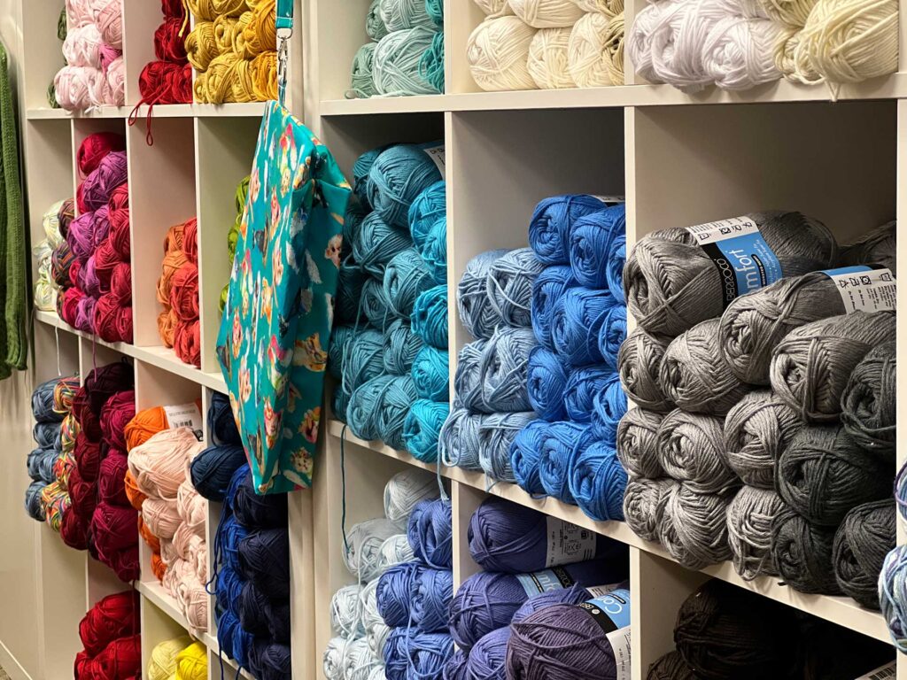Angled photo of wall of yarn skeins in blues, grays, and purples