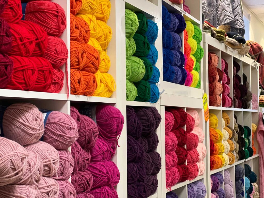Angled photo of wall of yarn skeins in a rainbow of colors