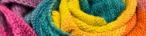 Close up of knitted fabric in colors of magenta, purple, teal, yellow and orange