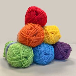 Balls of yarn stacked in a pyramid with red on top, orange and yellow in the middle and green, blue and purple on the bottom.